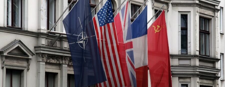 Die Flagge der Nato und Länderflaggen am ehemaligen Kontrollpunkt Checkpoint Charlie in Berlin.