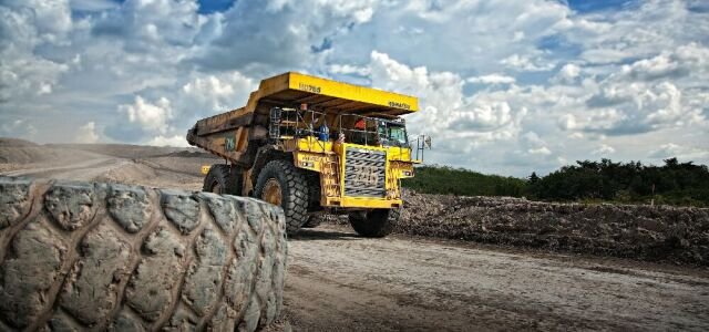 Gelber LKW beim Transport von Rohstoffen im Tagebau.  